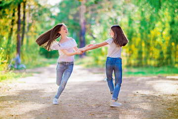 Two girls spinning holding hands, walking in the summer forest
