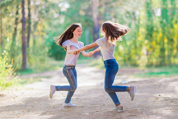 Two girlfriends circling holding hands, for a walk in the summer forest