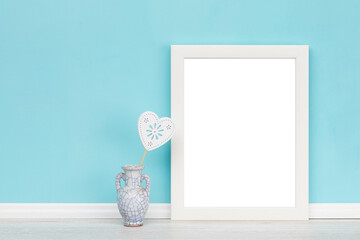 Poster mockup with vase, heart shaped ornament and white wooden vertical picture frame with...
