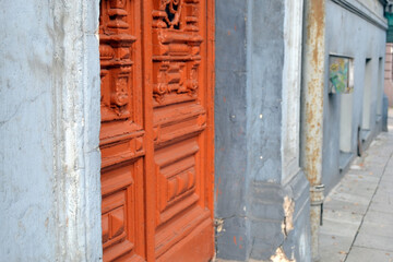 Selective focus on an old carved wooden door on a blurred stone wall background.