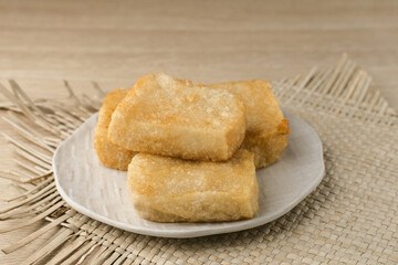 Jadah Goreng or Fried sticky rice cake is Javanese traditional cake made from glutinous rice and grated coconut. Served in white plate, selective focus image.
