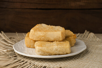 Jadah Goreng or Fried sticky rice cake is Javanese traditional cake made from glutinous rice and grated coconut. Served in white plate, selective focus image.
