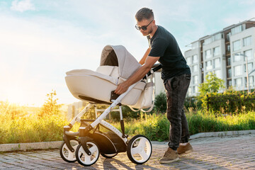 A young father lays out a stroller before walking with the baby. A man holds a cradle with a baby...