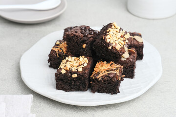 Homemade chocolate fudge brownie with mix topping, close up, served on plate, isolated on white background. Selective focus image.
