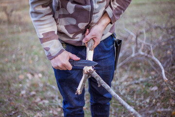 Man makes a slingshot with a knife from wooden stick