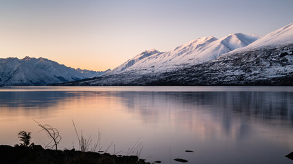 Snow-capped mountains reflected in Lake Ohau at sunset, Twizel, South Island.