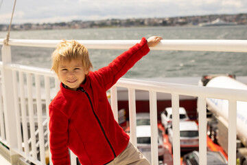 Obraz premium Children, experience ride on a ferry on a fjord, strong wind on the deck of a ferry on sunny day