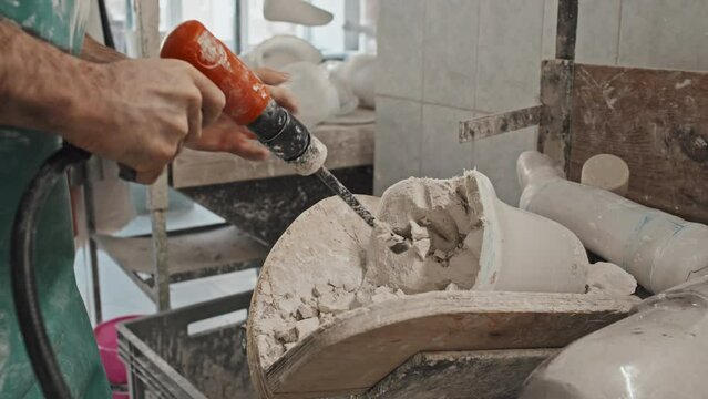 Unrecognizable craftsman removing plaster from prosthetic leg socket after casting it in modern workshop