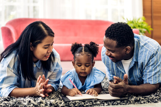 Portrait love black family african american father and mother with girl learn and study on table.Mom and dad with asian young girl writing with book make homework in homeschool at home.Education