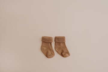 Pair of cozy hygge pastel colourful newborn baby socks on neutral beige background. Aesthetic minimalist baby fashion collage. Happy maternity concept