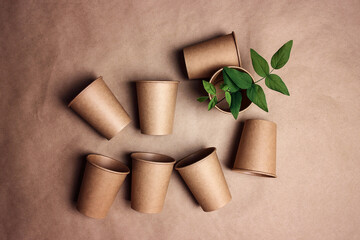Set of eco-friendly coffee to go cups with green leaves on brown paper background.
