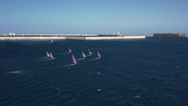 Windsurfing Race captured by drone in 4K. Fast windsurfing slalom race on hydrofoils. Extreme water sports. Windsurfing competition in Granadilla Harbour, Tenerife.