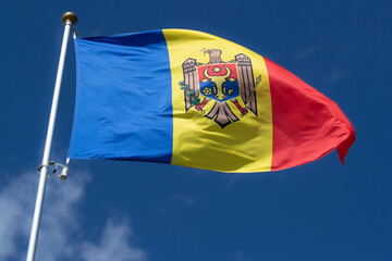 National flag of Moldova. The flag of  flies against a clear blue sky with white clouds. Close-up, perfect for news