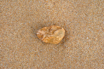 Close Up of Small Isolated Stone on Sandy Beach