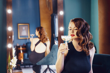 Posh elegant woman in evening dress with a glass of champagne in the luxury dressing room interior....