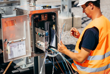 Adult electrical engineer inspect the electrical systems at the equipment control cabinet....