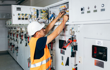 Adult electrician builder engineer testing and screwing equipment in fuse box and repairing of...