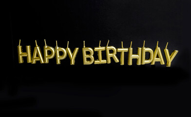 Golden Happy birthday  sign with candles on black background 