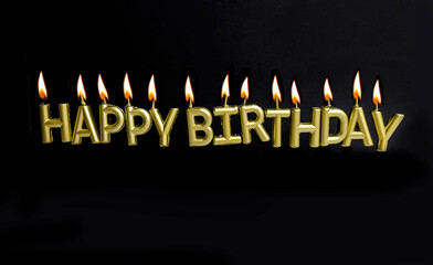 Happy Birthday Sign with Golden Candles with burning flames on Black Background
