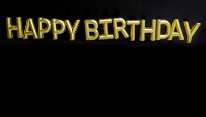 Golden Happy birthday  sign with candles on black background 