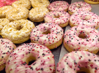 Assorted pink donuts in bakery shop