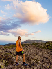 Fototapeta premium Man Standing on a Rocks in High Mountain with Orange Sunset Cloudy Sky .Vitosha Mountain ,Bulgaria 