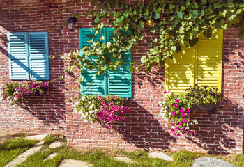 Beautiful brick house windows with colorful  shutters, flower pot and ivy, Provence, France 
