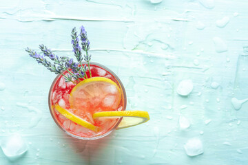 Fresh summer cocktail or mocktail with lemon and lavender, a cold citrus drink with ice, top shot on a blue background with copy space