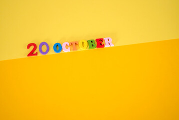 October 20 on a yellow, paper background with multicolored wooden letters with space for text.