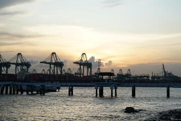 Fototapeta na wymiar sunset at the pier Trading seaport with cranes, cargoes and the ship harbour or port and container terminal sunset the seaside park Singapore