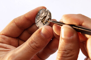 Closeup watchmaker's hands repairing mechanical watches isolated over white background. Concept of vintage retro mechanisms, job, work, ad