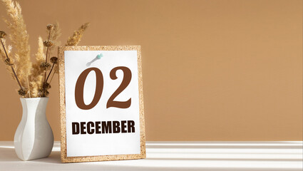 december 2. 2th day of month, calendar date.White vase with dead wood next to cork board with numbers. White-beige background with striped shadow. Concept of day of year, time planner, winter month