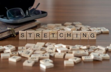 stretching word or concept represented by wooden letter tiles on a wooden table with glasses and a book - obrazy, fototapety, plakaty