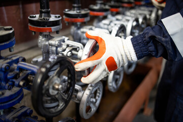 Fototapeta premium Close up view of worker's hands closing pipe valve in factory.