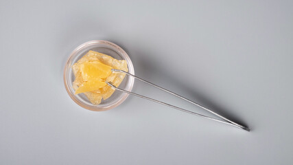 golden smoking cannabis wax and tongs on gray background.