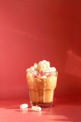 Cacao in a glass glass with marshmallows  on a pink background.