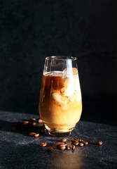 Coffee with ice and milk in a glass on a dark background
