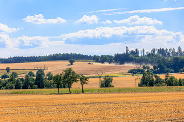 Fototapeta na wymiar A tractor works a dry field and drags a cloud of dust behind it