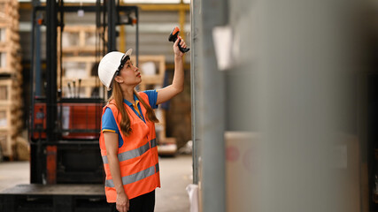 Female warehouse worker with barcode scanner in a large warehouse. Logistic industry concept
