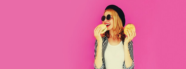 Portrait of happy smiling young woman with big burger fast food on pink background