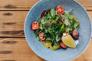 There are a blue bowl of salad on the table of the vegetarian restaurant.