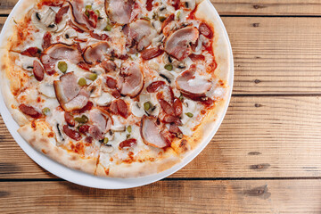 We can a pizza on the big white plate on the table of the pizzeria.