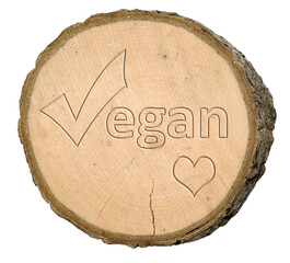 Tree disc or tree slice with bark on which the word vegan and a heart can be seen on a white background, isolated