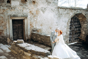 Sweet newlyweds walking around the grounds of the old castle on their wedding day in cold weather.