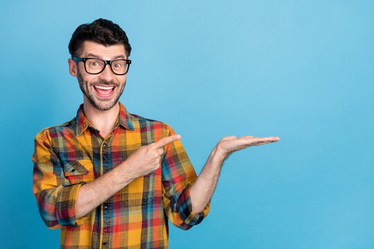 Photo of impressed bunet guy hold index empty space wear eyewear plaid shirt isolated on blue color background