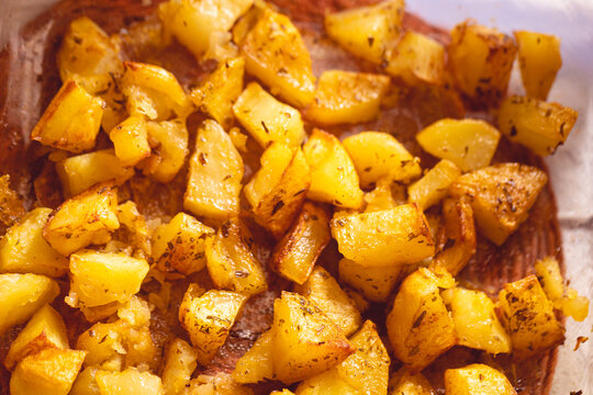 Batatas assadas ao forno com azeite de oliva e temperadas. Batata inglesa cortada em pedaços prontas para comer. Comida, alimento, carboidrato, assada.