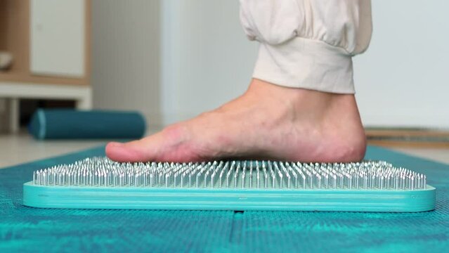 A woman stands on a sadhu board. Side view. Blue wooden board for meditation and soul harmonization. Take the first step in the practice of sadhu yoga