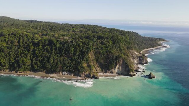 Slow aerial view of an ocean cliff and turquoise waters in Osa Peninsula, Costa Rica