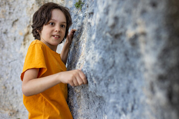 A little rock climber is training to climb a boulder