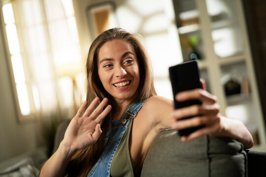 Happy young woman using the phone at home. Excited woman enjoying in the living room.